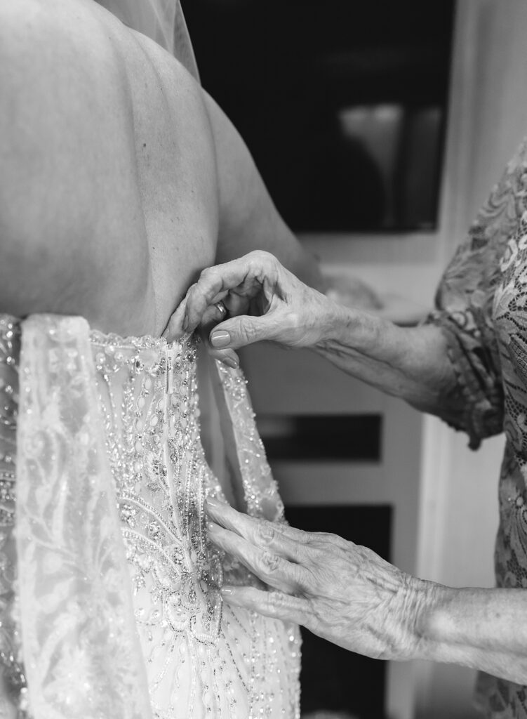 Black and white photo of woman's hands zipping up a wedding dress