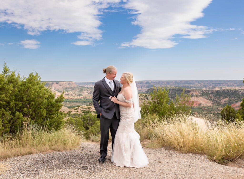 Man and woman in wedding attire looking at each other and smiling in Palo Duro State Park