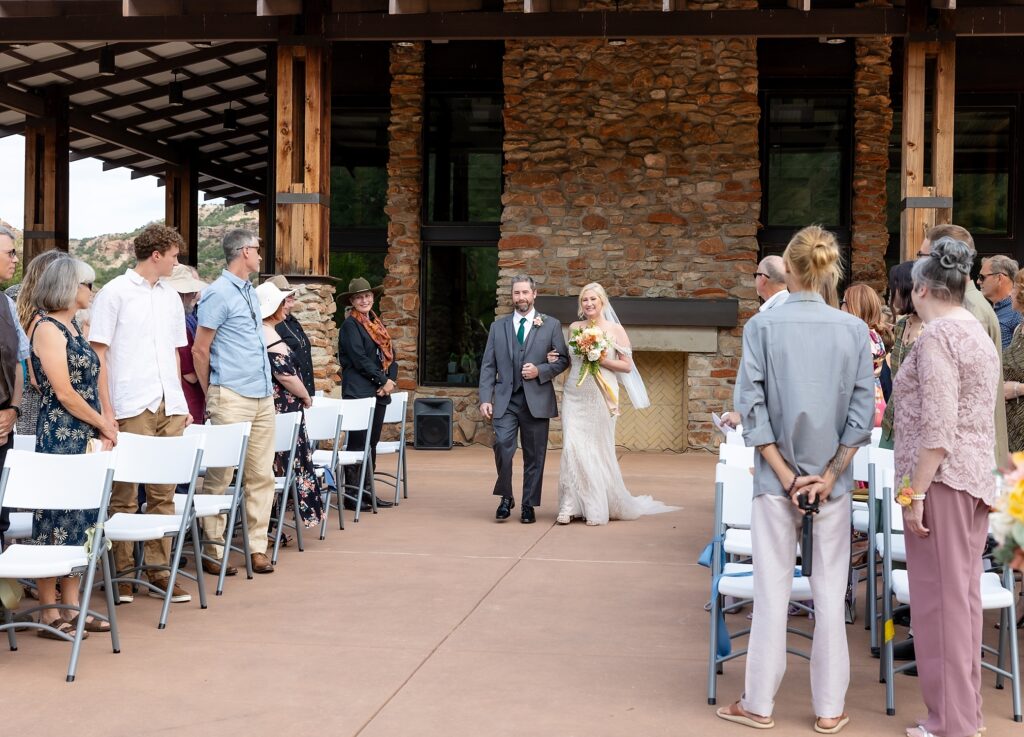 Man escorting bride down the aisle in outdoor wedding