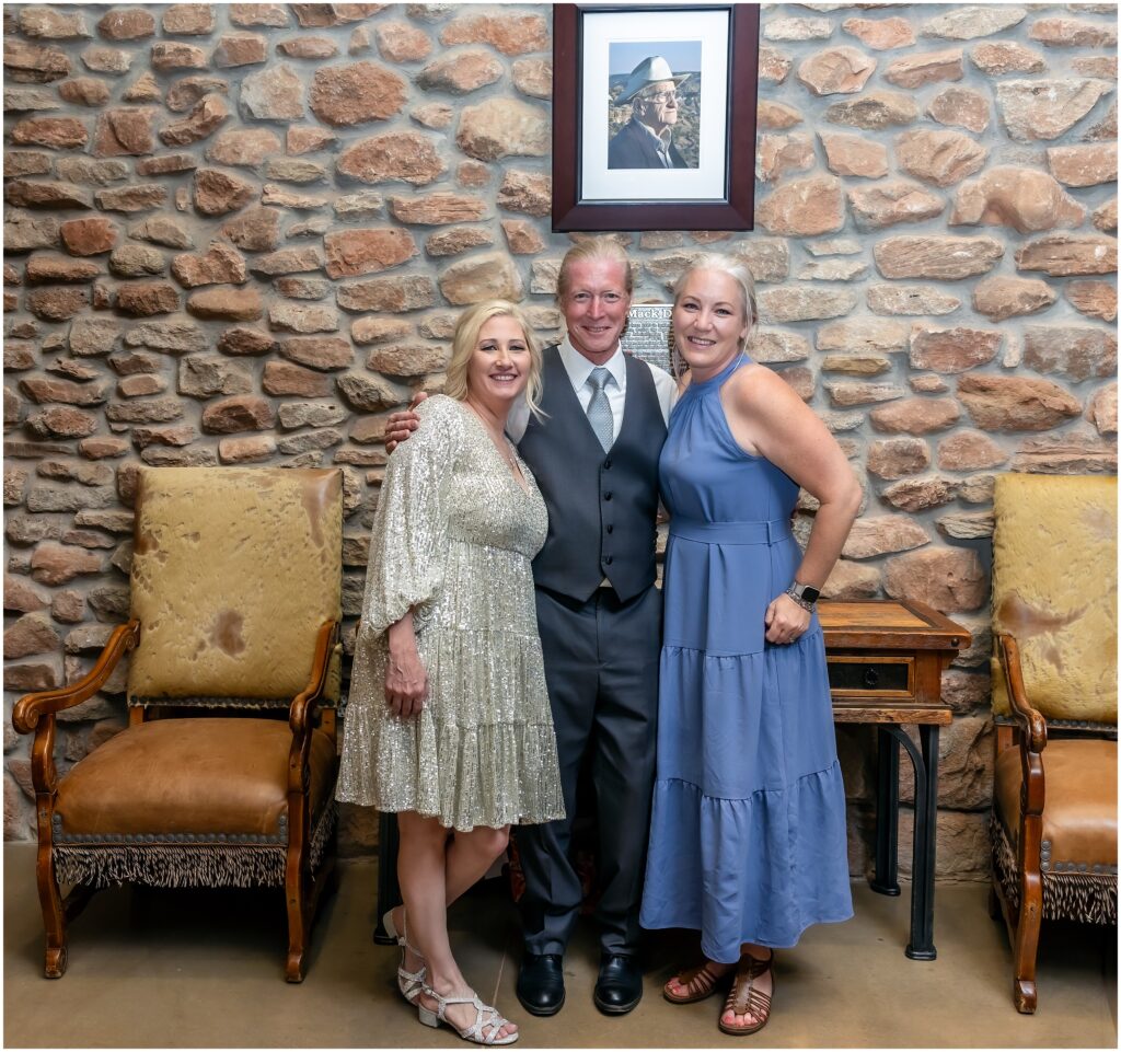 picture of man and two women smiling at the camera at a wedding reception