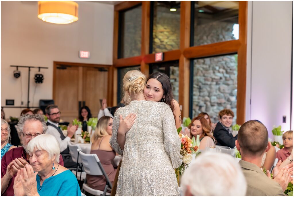 Bride hugging woman at a wedding reception after a speech